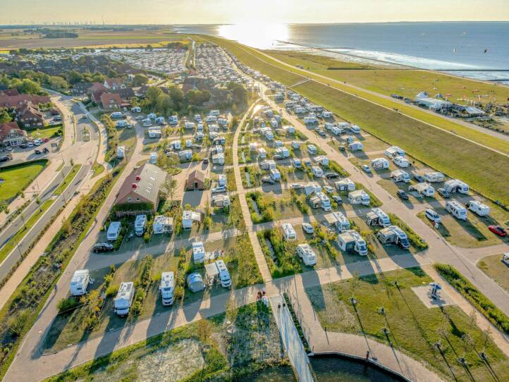 Luftaufnahme des Campingplatzes in Neuharlingersiel im abendlichen Gegenlicht. Gut zu sehen sind die neu angelegten größeren Parzellen sowie das Wegesystem. Die Mehrzahl der Stellplätze sind mit Wohnmobilien belegt.