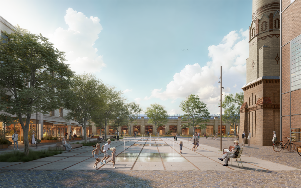 Zu sehen ist ein großzügiger, gepflasterter Stadtraum zwischen historischen Backsteinbauten. Rechts prägt ein markantes Gebäude mit industriellem Charakter den Platz, links und im Hintergrund schließen weitere Gebäude den Raum. In der Mitte öffnet sich eine weite Fläche, die vielfältig genutzt wird. Mehrere Menschen halten sich dort auf: Kinder spielen auf dem Boden, fahren Roller oder rennen über den Platz. Erwachsene sitzen auf Bänken, beobachten das Geschehen oder unterhalten sich. Bäume und niedrige Pflanzflächen gliedern den Platz und sorgen für Schatten und Grün. Die Szene vermittelt Lebendigkeit und Offenheit. Der Stadtraum ist nicht festgelegt auf eine einzige Nutzung, sondern lädt zum Spielen, Verweilen und Begegnen ein. Die landschaftsarchitektonische Gestaltung verbindet industrielle Geschichte mit einem zeitgemäßen, alltagstauglichen Freiraum für viele unterschiedliche Nutzer*innen.